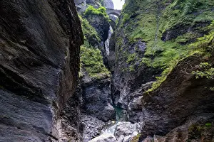 Trail Prints: Exploring a narrow canyon with steep rock walls and a bridge above in Switzerland