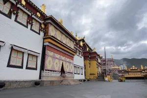 Traditions Prints: Exterior view of Songzanlin Monastery in Shangri-La City showcasing Tibetan design and mountain clouds