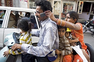 Images Dated 18th October 2009: Family of five on scooter, wife holding mobile phone for husband to take call