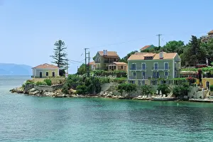 Vacation Destination Prints: Fiscardo village of low rise houses with red tiled rooftops by a beach with bathers