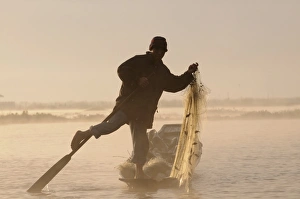 Fisherman holding his fishing net while rowing his little canoe, Inle lake Fisherman holding his fishing net while rowing his little canoe, Inle lake