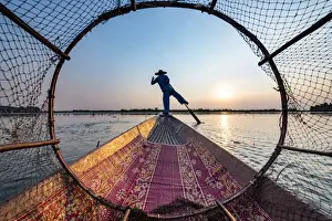 Fisherman at Inle Lake with traditional Intha conical net at sunset, fishing net