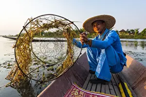 Fisherman at Inle Lake with traditional Intha conical net at sunset, fishing net