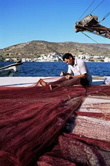 Cyclades Gallery: Fisherman mending nets on quayside at Katapola