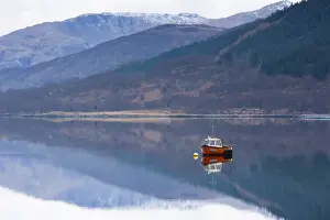 Fort William Prints: Flat calm Loch Levan with reflections of snow-capped mountains and small red fishing boat