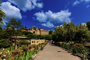 Cobblestone Prints: Flower-adorned bridge connects modern path to historic sights in Jajce under bright summer sky