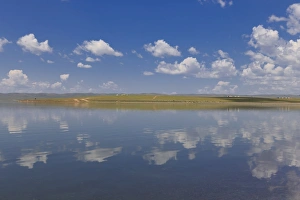 Fluffy clouds in a blue summer sky, reflected in a lake, distant reflected gers, Arkhangai