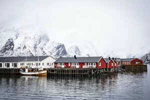 Nordland County Gallery: Foggy sky over snowcapped mountains and traditional Rorbu cabins by the sea, Hamnoy