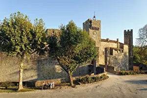 Gers Prints: Fortified village of Larresingle surrounded by ancient stone walls with visitors sitting nearby in late afternoon light