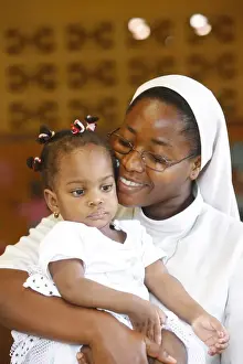 Cuddling Prints: Franciscan sister holding an orphan at nursery and kindergarten run by Catholic nuns