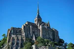 Walls Prints: French landmark Mont St. Michel stands on a rocky island under a clear blue sky in the region of Normandy in France