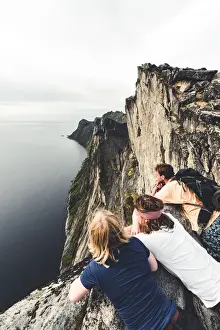 Adults Prints: Three friends enjoying the view of the fjord leaning on rocks on Segla mountain peak
