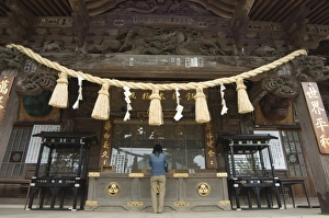 Worshipping Prints: Girl praying at shrine under giant rope