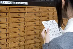 Asakusa Prints: A girl reads her omikuji (paper oracle) at Sensoji Temple in Asakusa, Tokyo, Japan, Asia