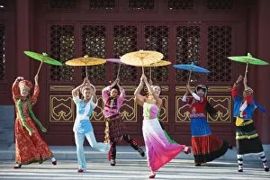 Girls dancing with coourful parasols at the Ethnic Minorities Park, Beijing, China, Asia