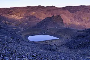 Granada Prints: Glacial lake Piedra de los Capuzones glows at dusk among rugged peaks in Sierra Nevada mountains in Granada