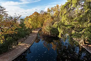 Granada Prints: Golden autumn foliage reflects in a pond within Carmen de los Martires gardens in Granada