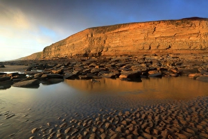 Tides Prints: Golden evening light on the cliffs in winter at Dunraven Bay