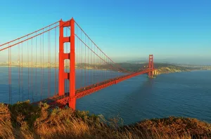 Iconic Prints: Golden Gate Bridge spans water in San Francisco at sunset with city skyline in distance