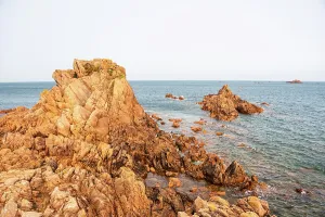 Vista Prints: Golden light shines on coastal rocks at Lions Rock in Guernsey during sunset over the Atlantic Ocean
