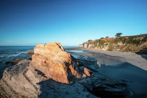 Zealand Prints: Golden morning light shines on cliffs and beach at Cape Foulwind in New Zealand