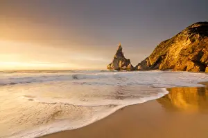 Cove Prints: Golden reflections of the cliffs on Praia da Ursa beach bathed by ocean at sunset