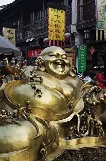 Small Prints: A golden statue of a reclining laughing Buddha covered in small Buddhas