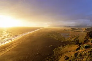 Panoramas Prints: Golden sunset over Dyrholaey coastline with waves breaking on black sand beach