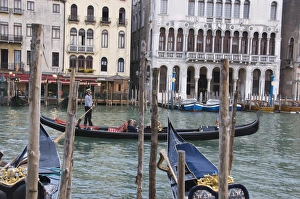Gondola passing moorings at Riva del Vin on the Grand Canal, Rialto, Venice Gondola passing moorings at Riva del Vin on the Grand Canal, Rialto, Venice
