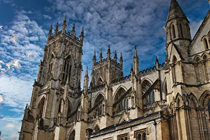 Gothic cathedral tower against a dramatic cloudy sky, showcasing intricate architectural details and spires, ideal for historical or religious themes in York, North Yorkshire, England