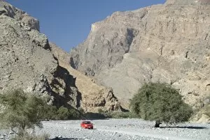Gravel road along the floor of deep wadi below limestone cliffs, Wadi Bani Habib