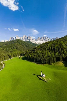 Dolomites Gallery: Green forest and meadows surrounding the small Ranui church and Odle in spring, aerial view