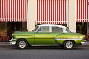 Multi Colored Prints: Green vintage American car parked in front of cafe, Cienfuegos, UNESCO World Heritage Site