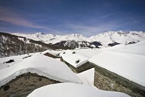 Group of mountain huts covered in snow under a starry night in Valle Spluga, Vachiavenna, Lombardy, Italy, Europe
