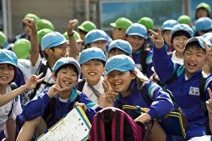 Group of smiling Japanese elementary school children wearing blue and green caps