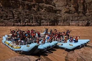 Happy tourists on two rafts celebrating, in the beautiful scenery of the Colorado River in the Grand Canyon, Arizona