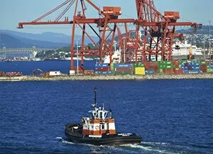 Harbour tug with containers and cranes in the background, in Vancouver