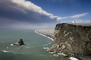 Eruption Prints: Headland with lighthouse at Dyrholaey looking towards a black volcanic sand beach stretching 15 miles into the distance