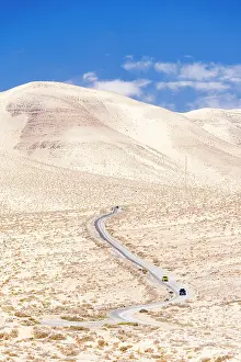 Dirt Prints: High angle view of cars driving on a winding desert road in the barren landscape