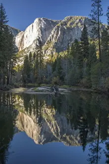 High granite cliffs reflected in the tranquil Merced River, autumn, Yosemite Village