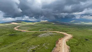 Grassland Prints: Highland view of Qarabaqh showing winding roads and vast green fields under cloudy skies in Azerbaijan