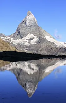 Hiker admiring the Matterhorn reflected in Lake Stellisee, Zermatt, Canton of Valais