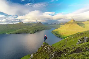 Mid Adults Prints: Hiker with backpack enjoying the view standing on rocks overlooking Funningur fjord