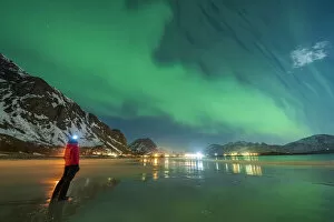 Nordland Gallery: Hiker with head torch watching the Aurora Borealis (Northern Lights) standing on Ramberg beach