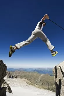 Images Dated 21st August 2010: Hiker jumping across a gap in the rocks, Pico de Aneto, the highest peak in the Pyrenees