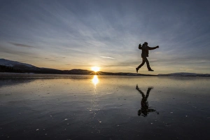 Hiker jumps on the frozen surface of Lake Limingen, Rorvik, Borgefjell National Park