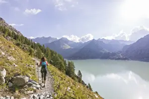 The Great Outdoors Prints: Hiker on path towards Rifugio Bignami beside the dam and water basin of Alpe Gera