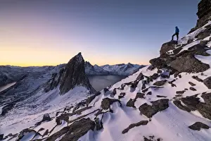 Winter Scene Prints: Hiker on peak Hesten admires Mount Segla and the Mefjorden framed by frozen sea at sunrise
