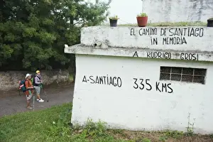 Asturias Prints: Hiker pilgrims looking at a distance marker to Santiago de Compostela