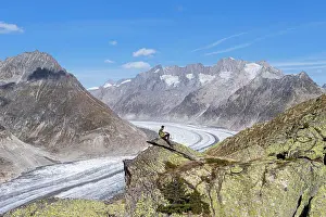 Mid Adults Prints: Hiker on top of a rock enjoying the view of the Aletsch Glacier and alpine mountains with snow